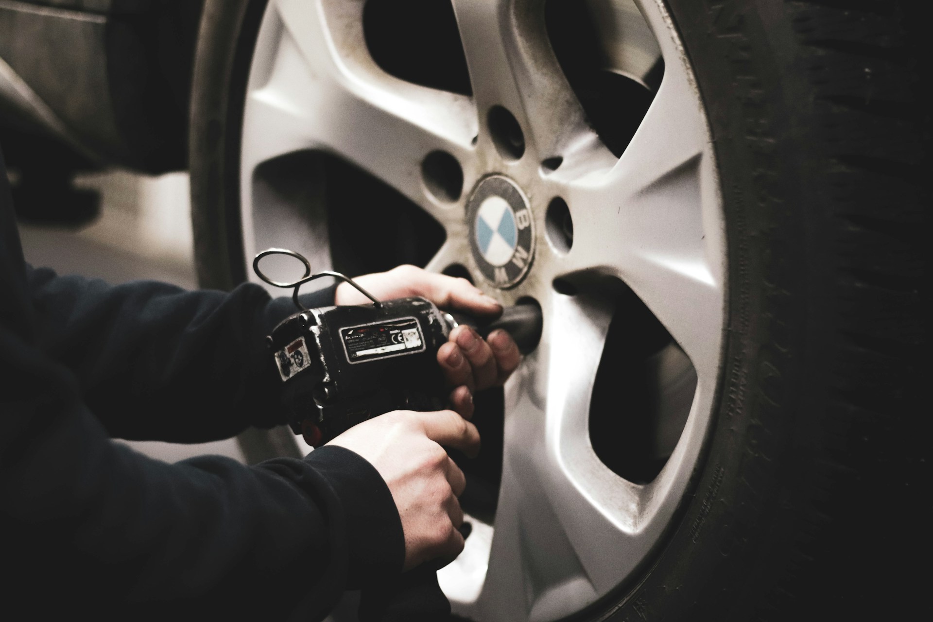 Close-up of mechanic's hands working on a BMW alloy wheel