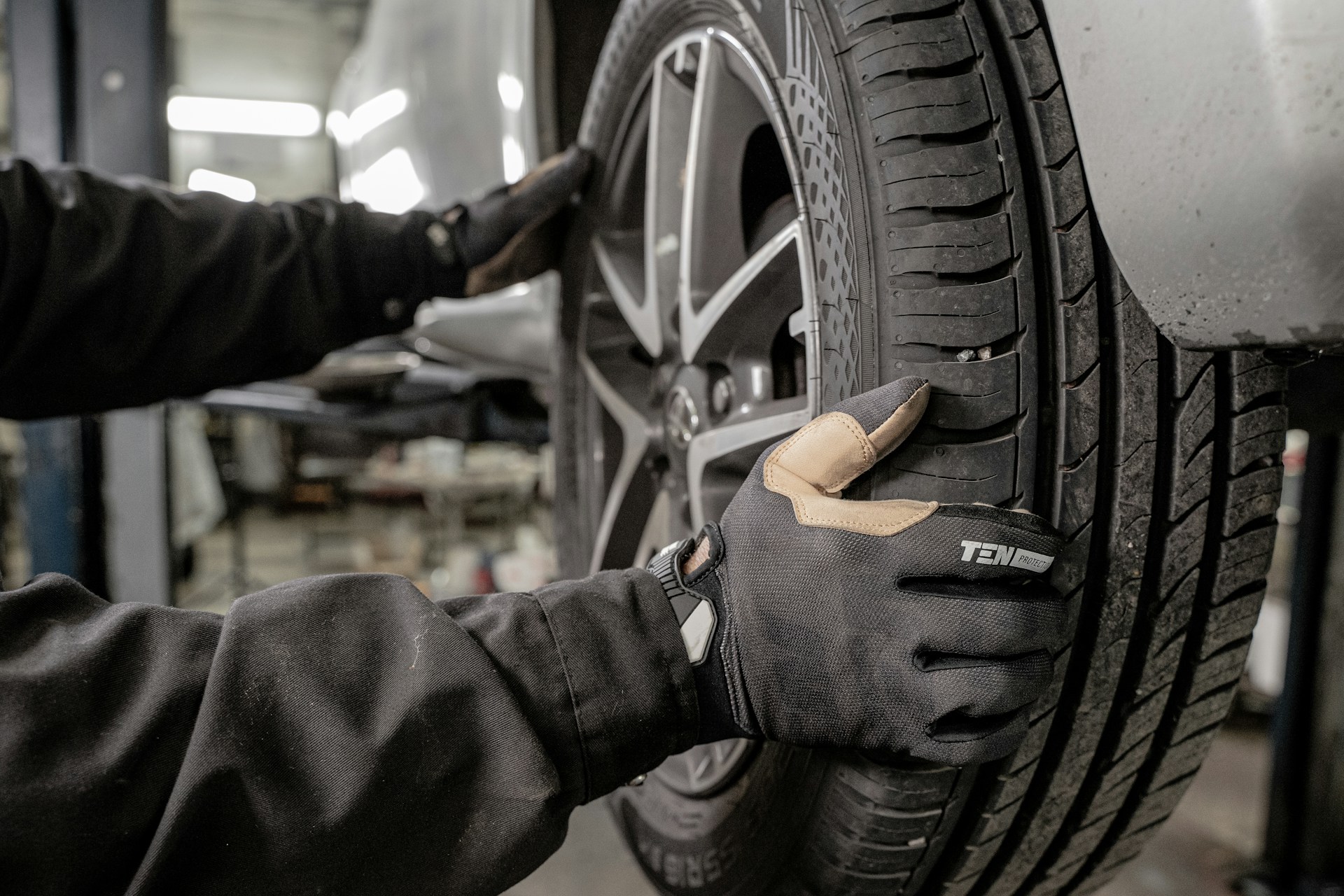 Mechanic in heavy gloves inspecting a tire and alloy wheel
