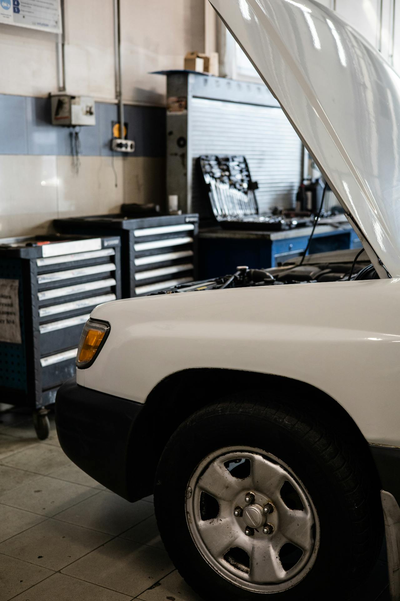 A white SUV with hood raised inside Howard's Auto Repair garage bay